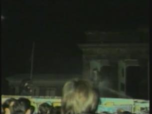M&auml;nner auf der Mauer werden am Brandenburger Tor von hinten mit Wasser bespritzt